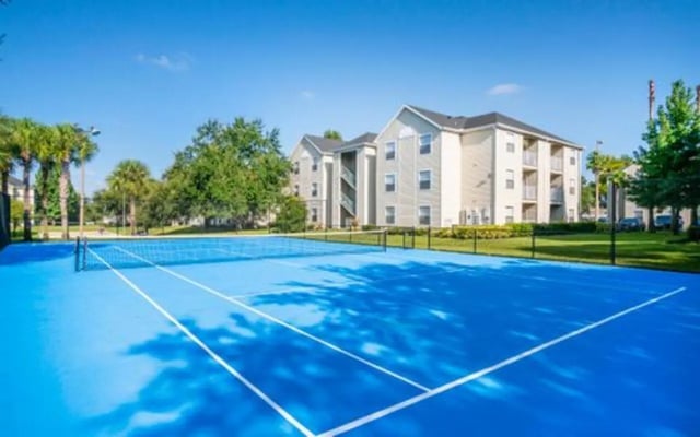 Blue tennis court with apartment buildings exterior at The Pointe at Central in Orlando Student Accommodation