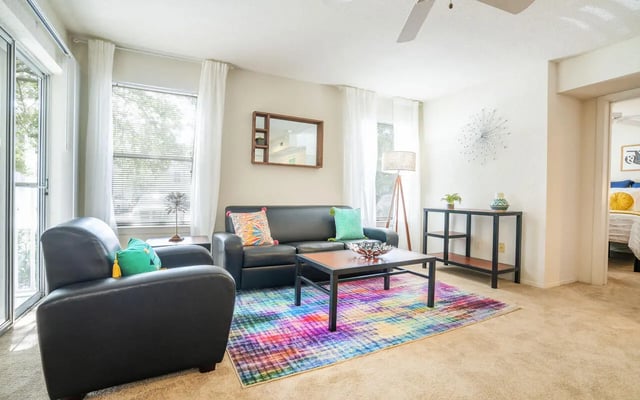 Sofa armchair coffee table colorful rug living room at The Pointe at Central in Orlando Student Accommodation