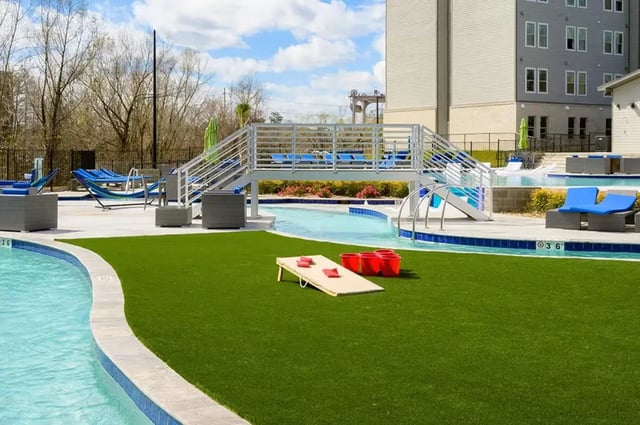 Cornhole game and buckets by pool exterior at The Pointe at Pinhook in Lafayette Student Accommodation