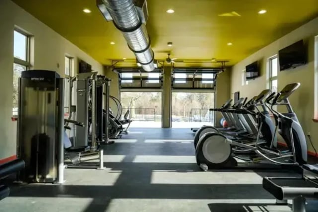 Gym equipment in open garage gym room at The Pointe at Pinhook in Lafayette Student Accommodation