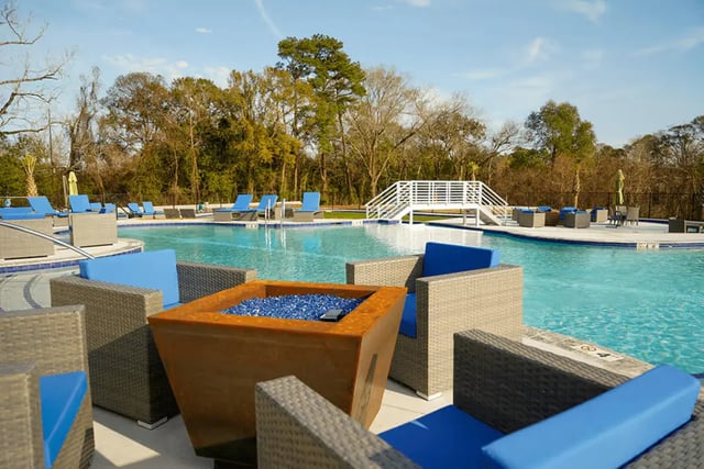 Wicker chairs blue cushions fire pit resort pool at The Pointe at Pinhook in Lafayette Student Accommodation