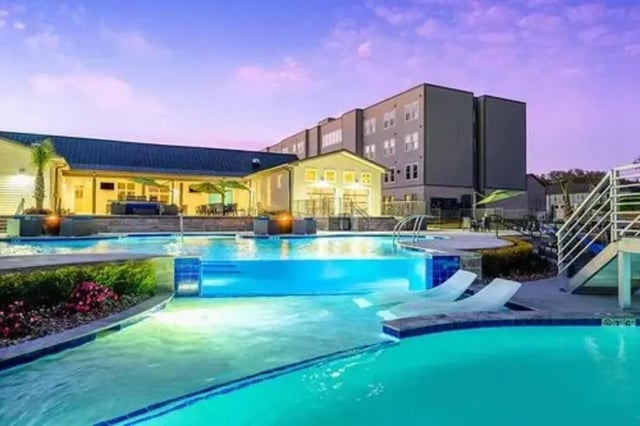 Modern apartment building with glowing pool exterior at The Pointe at Pinhook in Lafayette Student Accommodation
