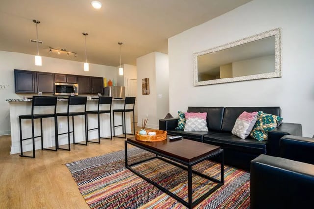 Sofa coffee table bar stools kitchen living room at The Rocks in East Lansing Student Accommodation