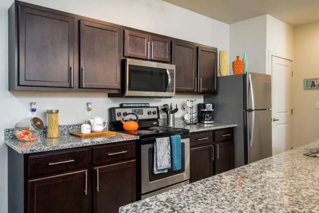 Dark cabinets microwave oven and refrigerator kitchen at The Rocks in East Lansing Student Accommodation