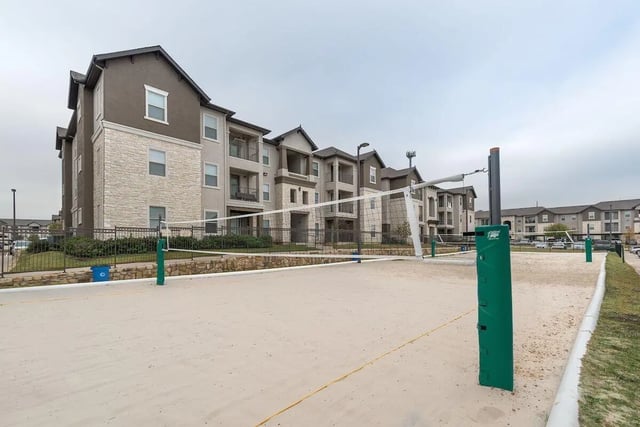 Volleyball court with apartment buildings exterior at Forum at Denton Station in Denton Student Accommodation