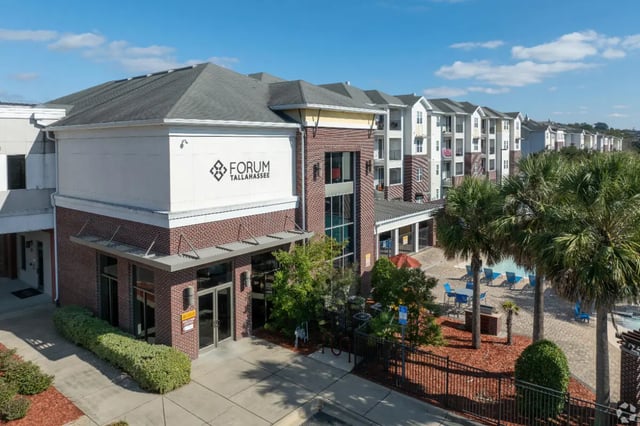 Forum Tallahassee building with pool and palm trees exterior at Forum at Tallahassee in Tallahassee Student Accommodation