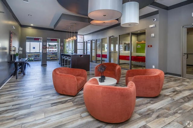 Orange armchairs around a white coffee table lounge at Forum at Tallahassee in Tallahassee Student Accommodation