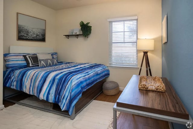 Bed with blue striped bedding and wall art Bedroom at Forum at Tallahassee in Tallahassee Student Accommodation