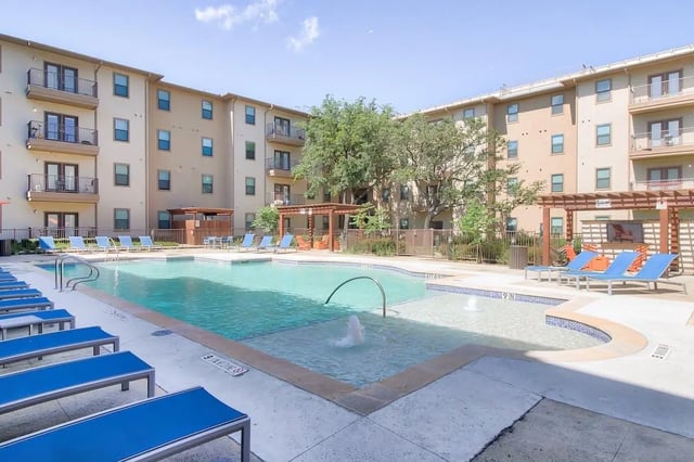 Apartment building with swimming pool and lounge chairs exterior at Prado Student Living in San Antonio Student Accommodation