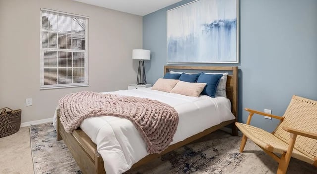 Bed with knit blanket artwork chair bedroom at 403 West in Raleigh Student Accommodation