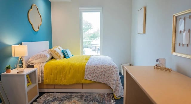 Bed pillows desk lamp and gold mirror bedroom at Cheatham Street Flats in San Marcos Student Accommodation