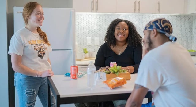 Three students talking by table kitchen at Cheatham Street Flats in San Marcos Student Accommodation