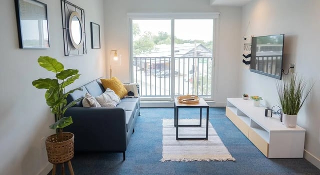Sofa pillows plant coffee table rug TV media console living room at Cheatham Street Flats in San Marcos Student Accommodation