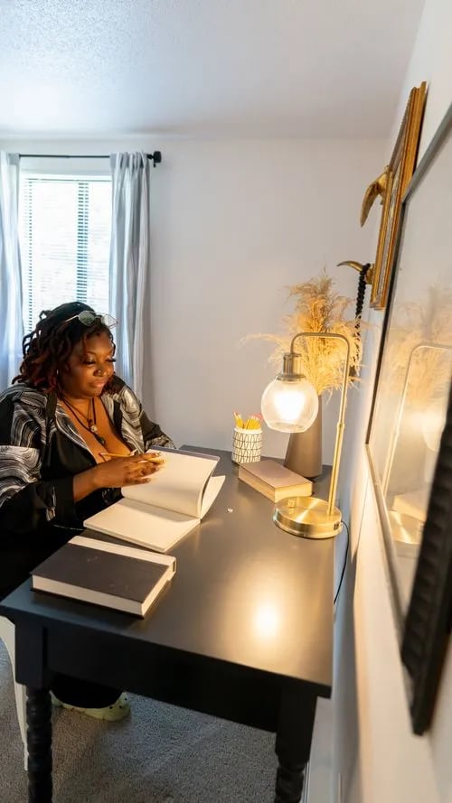 Woman studying at desk with books and lamp Study area at The Den Cedar Ridge in Willington Student Accommodation