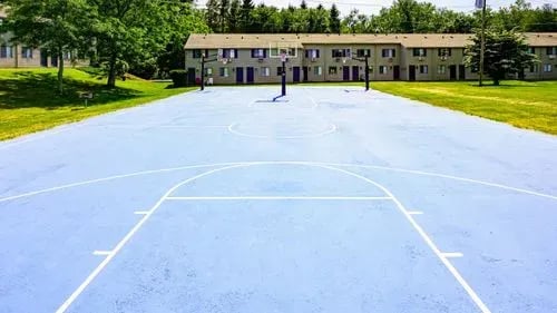 Blue basketball court with hoop near buildings playing area at The Den Cedar Ridge in Willington Student Accommodation