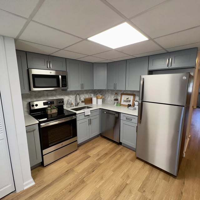 Gray cabinets stainless steel appliances wood floor kitchen at The Den Cedar Ridge in Willington Student Accommodation
