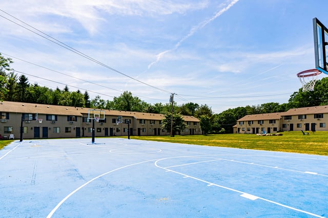 Blue basketball court with two hoops exterior at The Den Cedar Ridge in Willington Student Accommodation