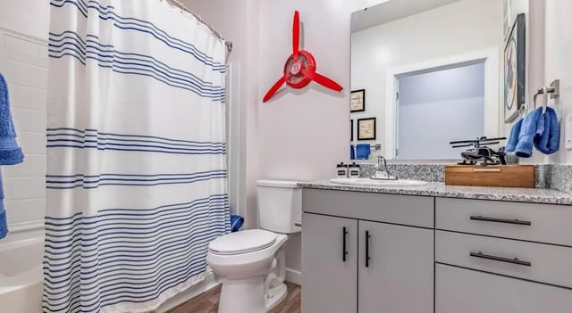 Striped shower curtain toilet vanity sink helicopter model bathroom at The Vanguard in Cincinnati Student Accommodation