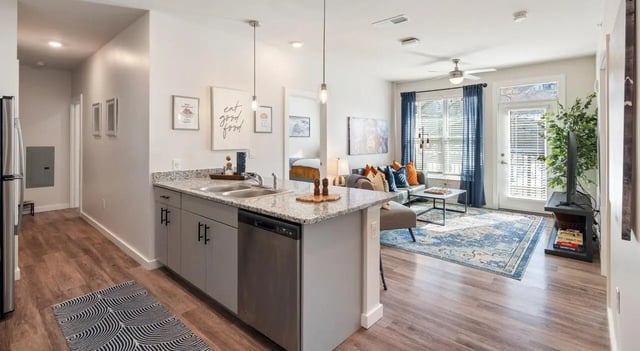 Kitchen island with sink dishwasher and living area living room at The Vanguard in Cincinnati Student Accommodation