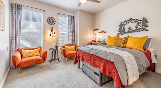 Two orange chairs bed desk lamp wall art Bedroom at The Vanguard in Cincinnati Student Accommodation