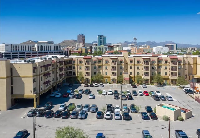 Apartment building with parking lot and city skyline exterior at The Junction At Iron Horse Student Housing in Tucson Student Accommodation