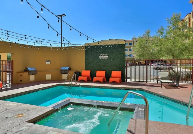 Pool hot tub grills orange chairs and lounge chair outdoor area at The Junction At Iron Horse Student Housing in Tucson Student Accommodation
