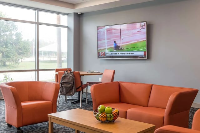 Orange couches TV table and chairs living room at Campus Walk Apartments in Buffalo Student Accommodation