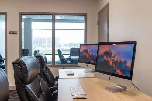 Study room with iMac computers and leather chairs at Campus Walk Apartments in Buffalo Student Accommodation
