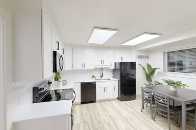 White cabinets black appliances dining table kitchen at Bountiful Court Apartments in Provo Student Accommodation