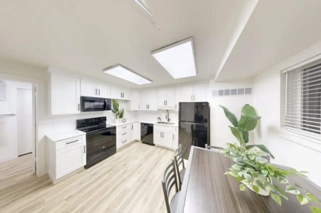 White kitchen with black appliances and dining table kitchen at Bountiful Court Apartments in Provo Student Accommodation