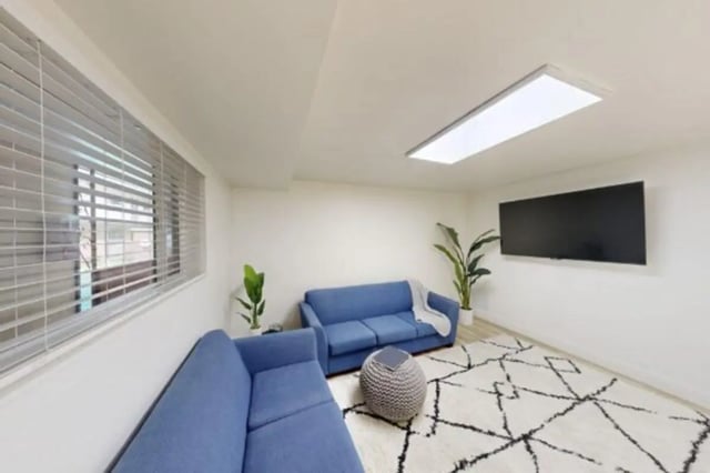 Two blue sofas ottoman rug and TV living room at Bountiful Court Apartments in Provo Student Accommodation