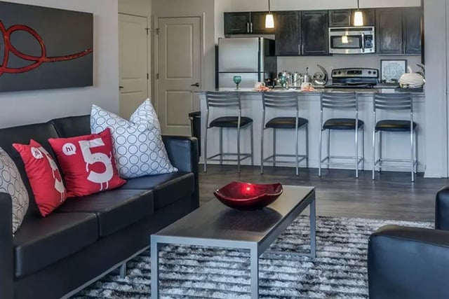 Black sofa pillows art bar stools and kitchen living room at The Edge at Conway in Conway Student Accommodation