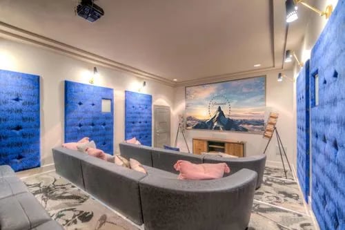 Curved sofas with pink pillows theatre projector screen living room at The Reserve San Antonio in San Antonio Student Accommodation
