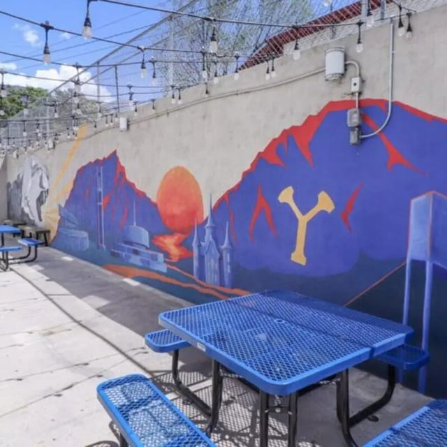 Blue picnic tables mural wall string lights outdoor area at Campus Way in Provo Student Accommodation