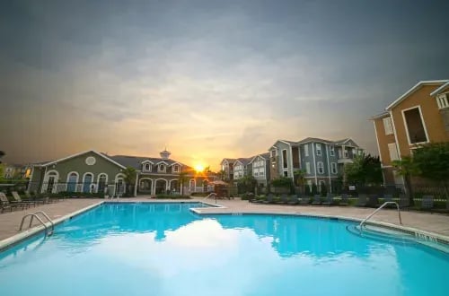 Large swimming pool with lounge chairs and buildings exterior at The Letterman Greensboro in Greensboro Student Accommodation