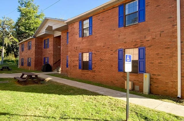 Brick building with picnic tables and blue shutters exterior at Bradford Oaks Apartments in Tallahassee Student Accommodation