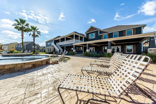 Poolside lounge chairs with palm trees and building exterior at The Reserve at College Station in College Station Student Accommodation