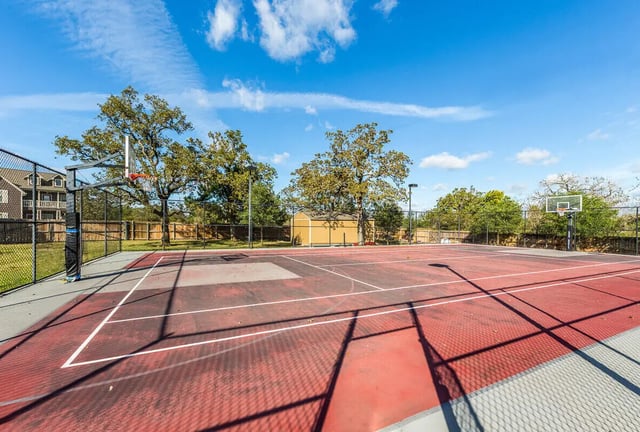 Basketball court with trees and building exterior at The Reserve at College Station in College Station Student Accommodation