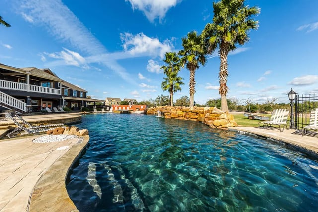 Poolside with palm trees and building exterior at The Reserve at College Station in College Station Student Accommodation