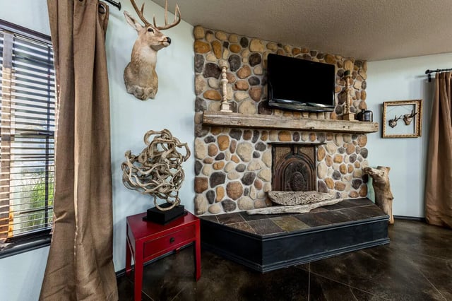 Stone fireplace mounted TV deer head artwork living room at The Reserve at College Station in College Station Student Accommodation