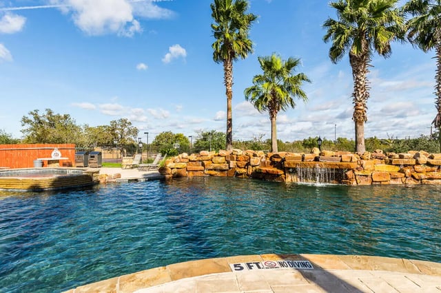 Palm trees pool waterfall stone wall exterior at The Reserve at College Station in College Station Student Accommodation