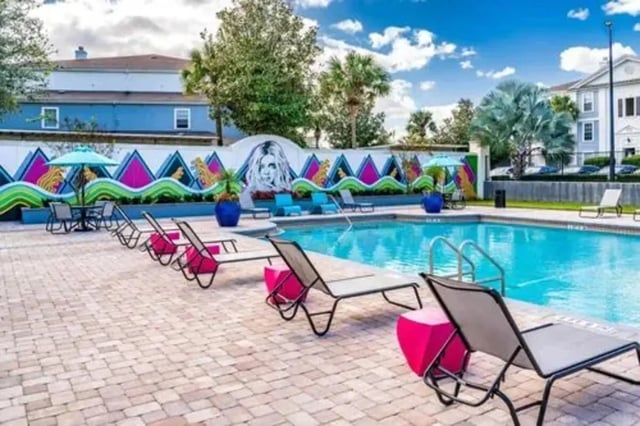 Pool with lounge chairs and colorful mural exterior at Arden Villas in Orlando Student Accommodation