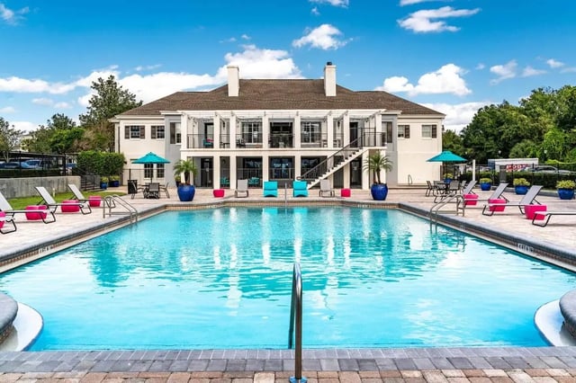 Large swimming pool with lounge chairs and building exterior at Arden Villas in Orlando Student Accommodation