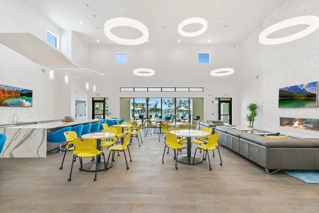 Bar tables yellow chairs lounge sofa fireplace living room at The Residences at University Village in Fort Myers Student Accommodation