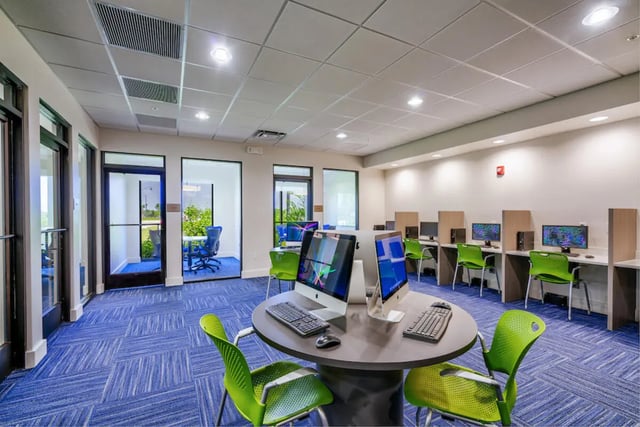 Computers and green chairs at workstations computer lab at The Residences at University Village in Fort Myers Student Accommodation