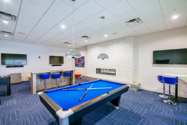 Pool table bar stools televisions recreation room at The Residences at University Village in Fort Myers Student Accommodation