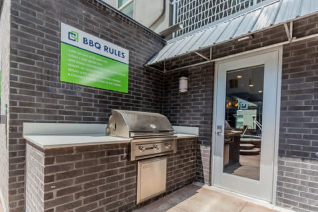 BBQ grill on brick counter with rules sign exterior at CollegePlace Provo in Provo Student Accommodation