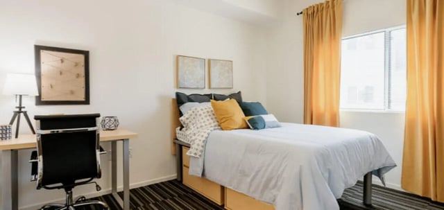 Bed desk lamp artwork and gold curtains bedroom at The Vista in Turlock Student Accommodation