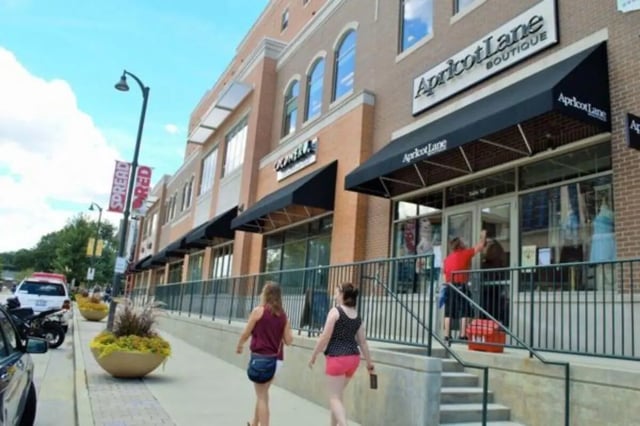 Two women walk past stores exterior at CollegePlace Uptown