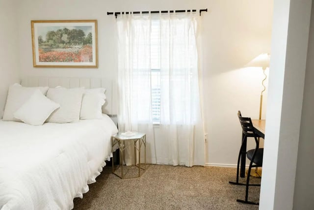 White bed painting side table desk chair lamp bedroom at The Lodge Apartments in San Marcos Student Accommodation